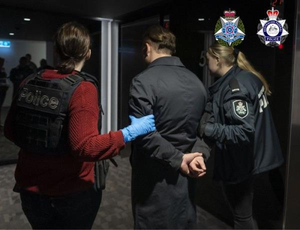 Australian Federal Police escort one of six people arrested in the smuggling case so far, in Melbourne, Australia.